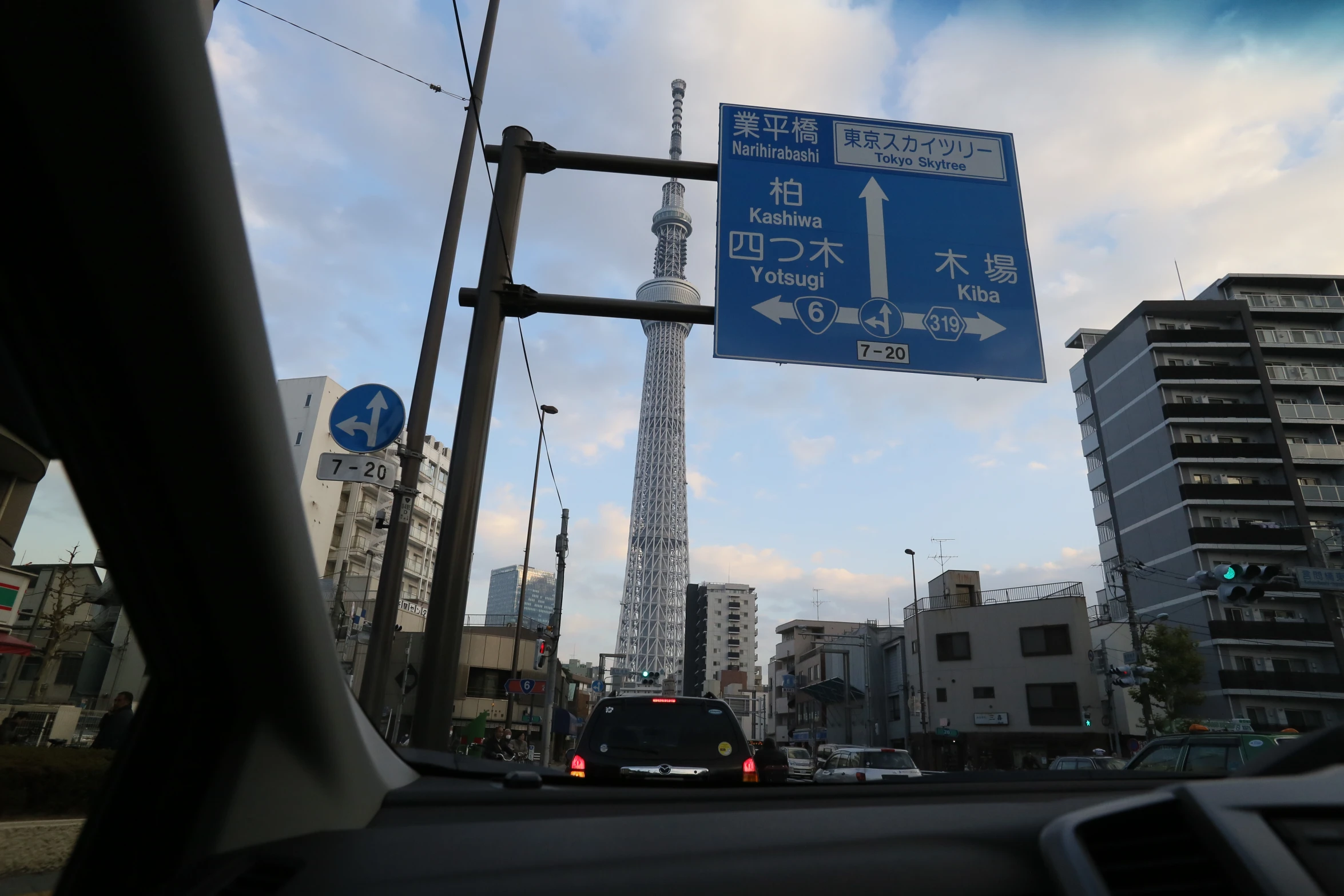 a street sign posted next to a pole with cars parked on it