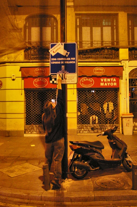 a person standing next to a sign with a motorcycle parked beside it