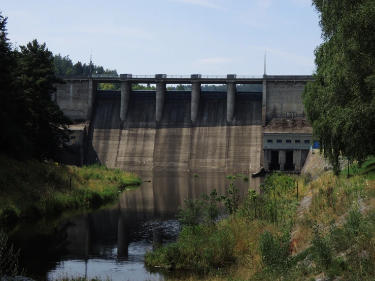 a large brick dam and water reservoir under a blue cloudy sky