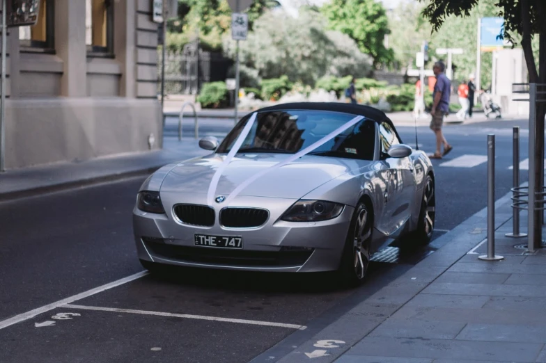 the grey bmw z4 roadster is parked by the curb