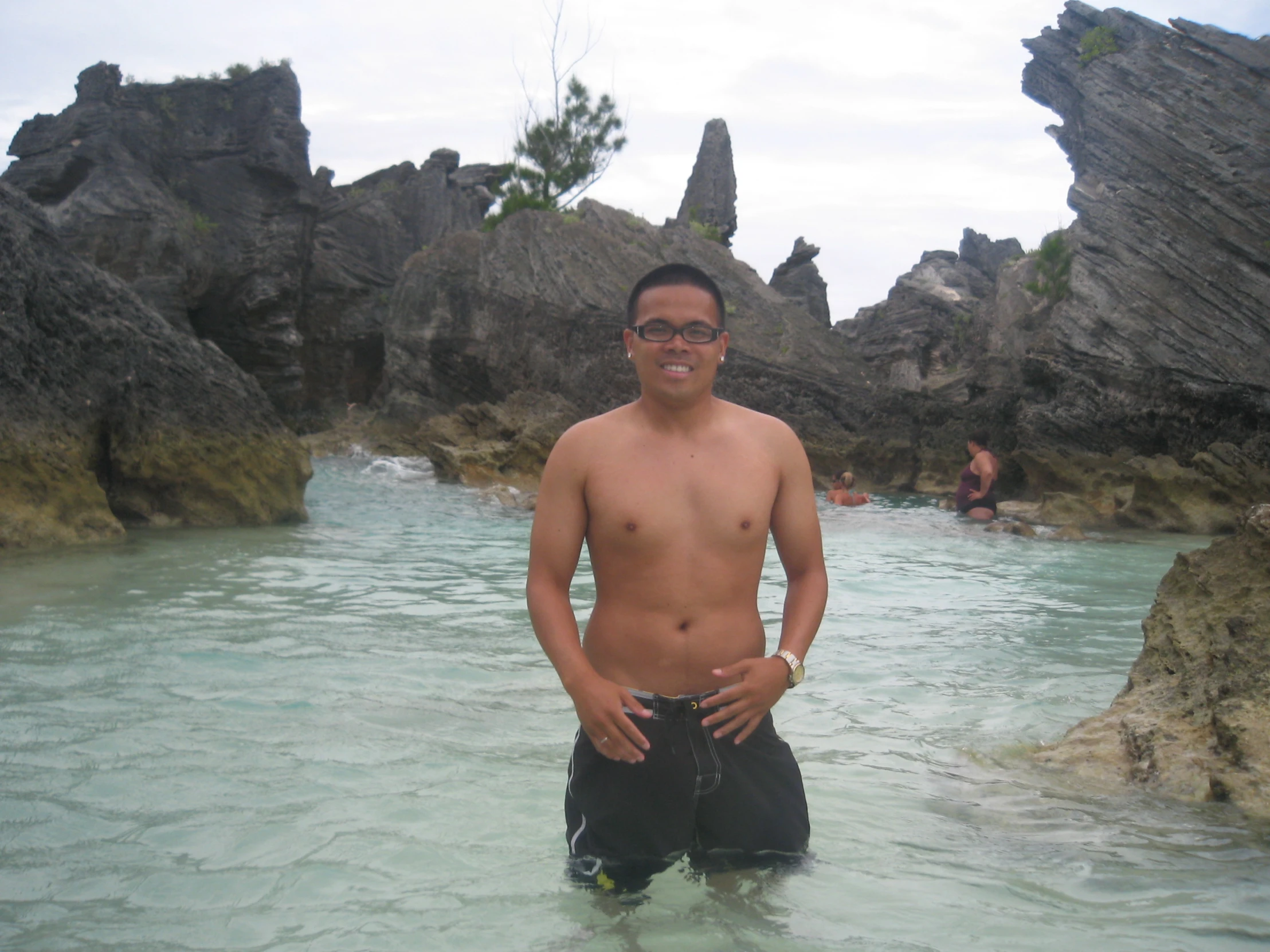 a man standing in a body of water with rocky shore