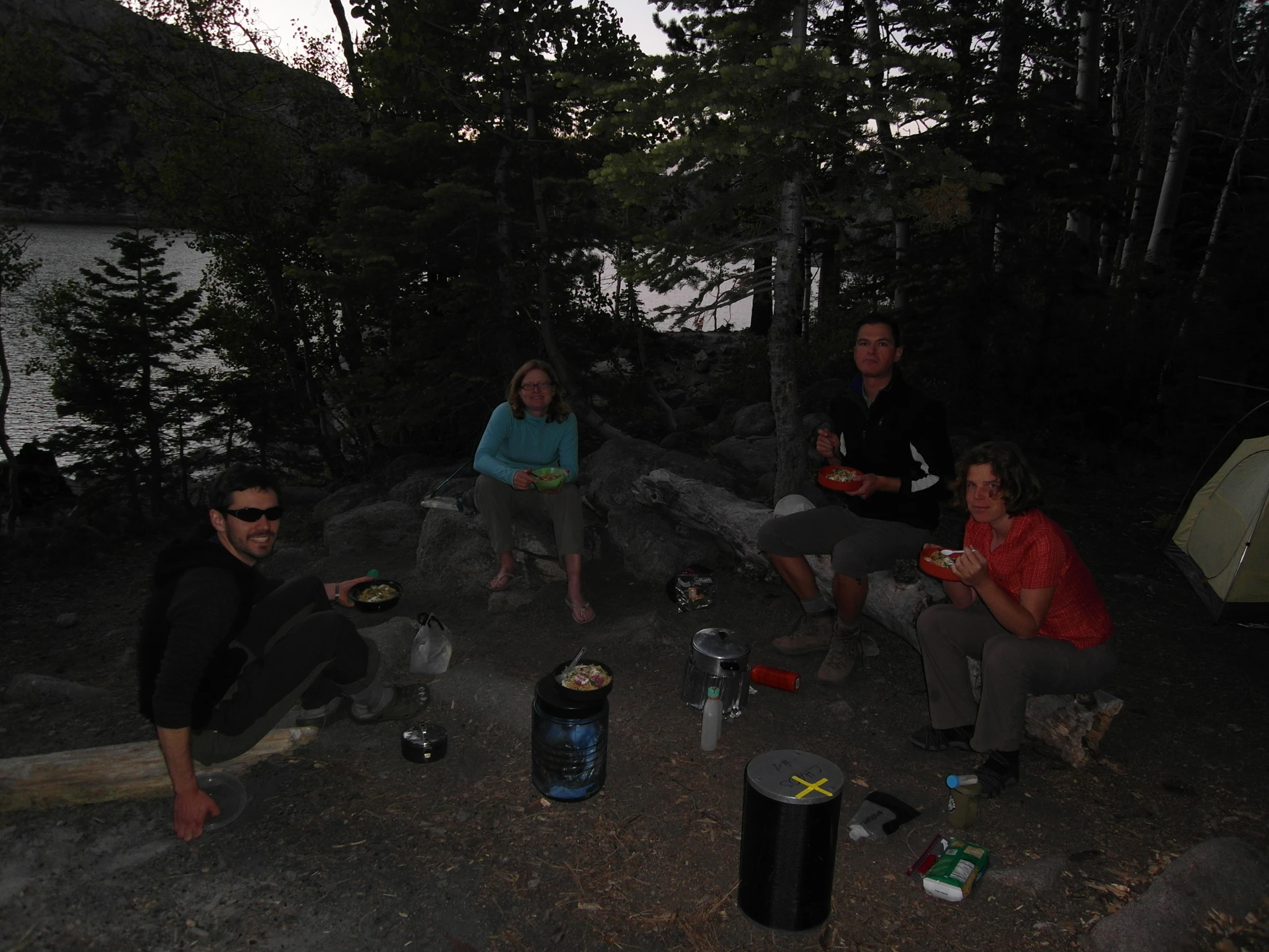 a group of people sitting on the side of a road near a lake