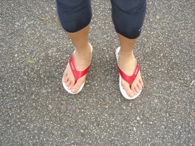 a close up of a person wearing red and white sandals