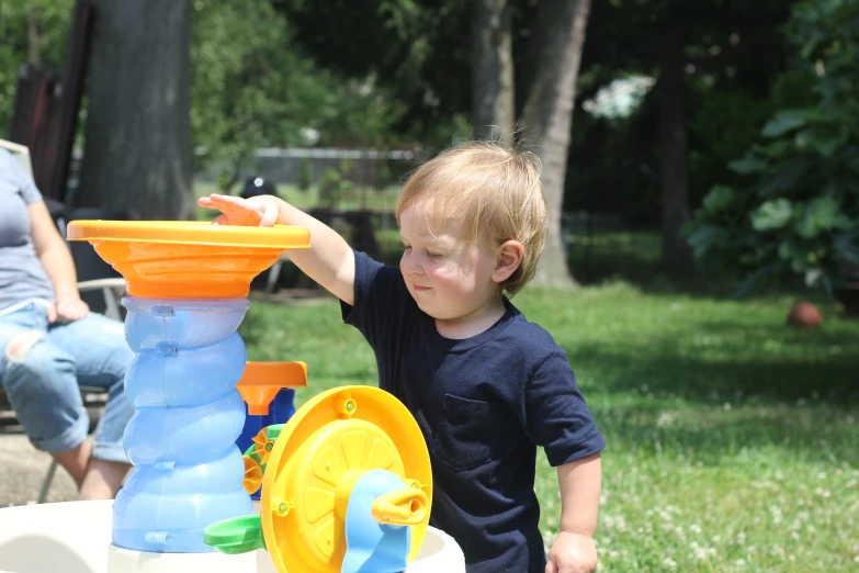 a little boy holding a water sprinkler and water