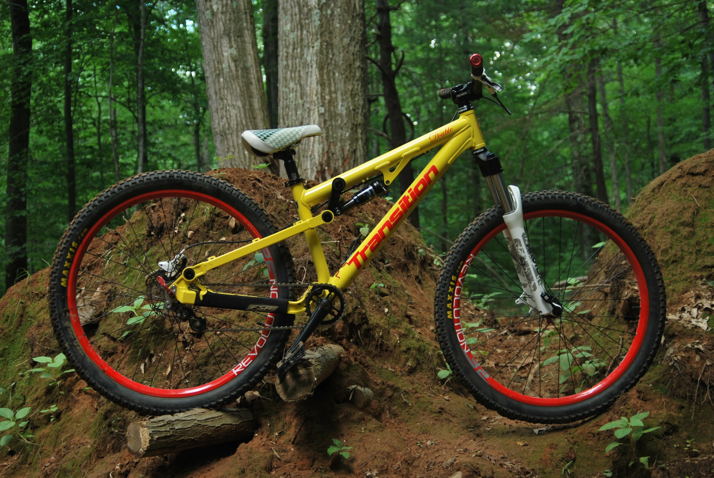 a yellow and red mountain bike on the side of a dirt trail