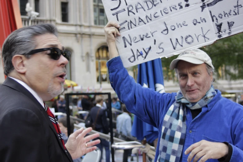 two men wearing ties and hats are holding a sign