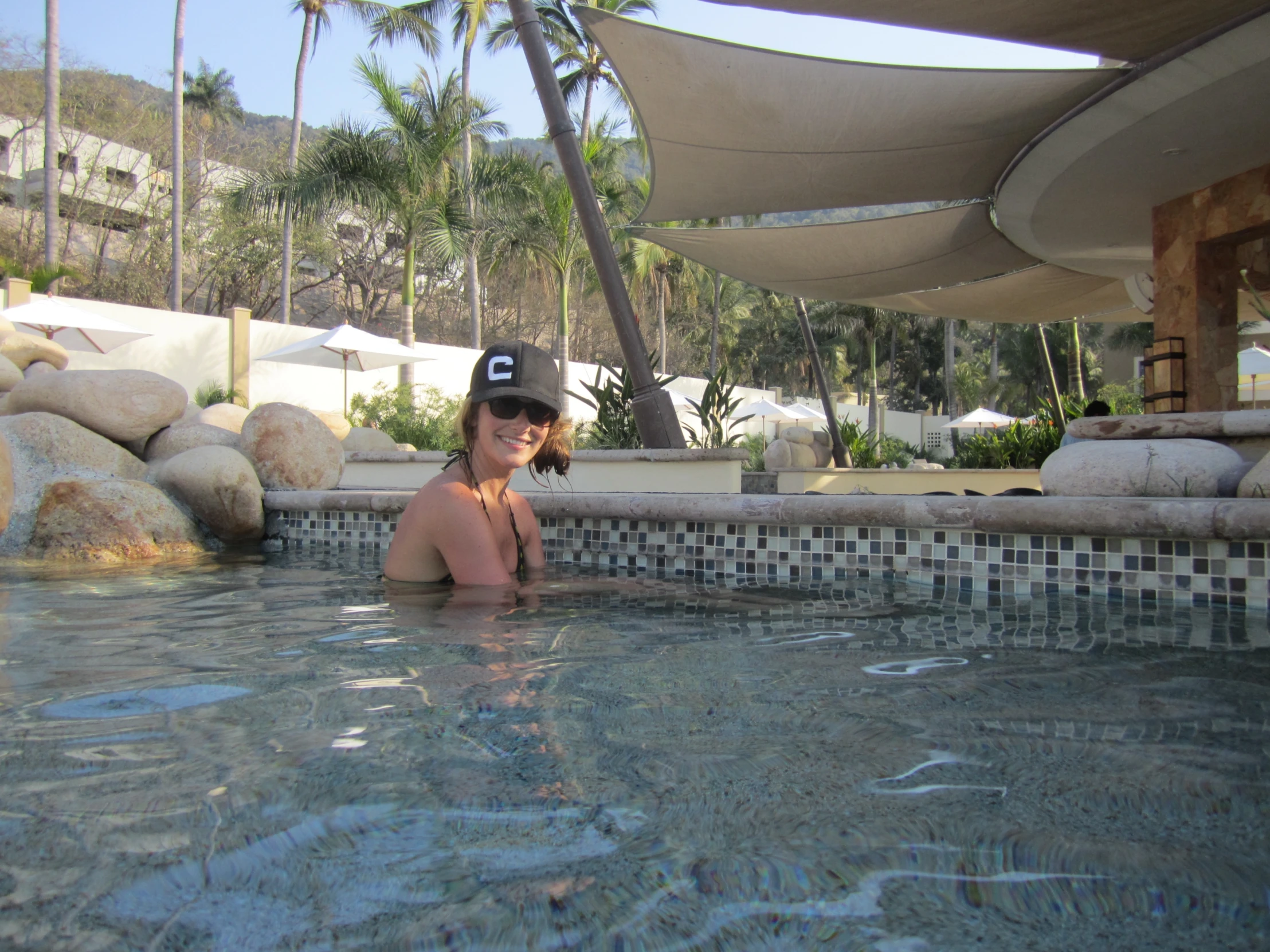 a woman sitting by the edge of a swimming pool