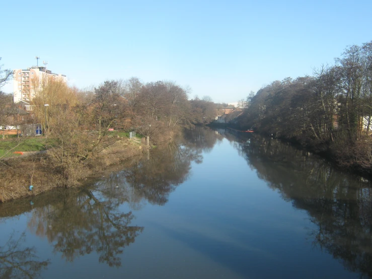 a narrow river with a clear blue sky and a city in the distance