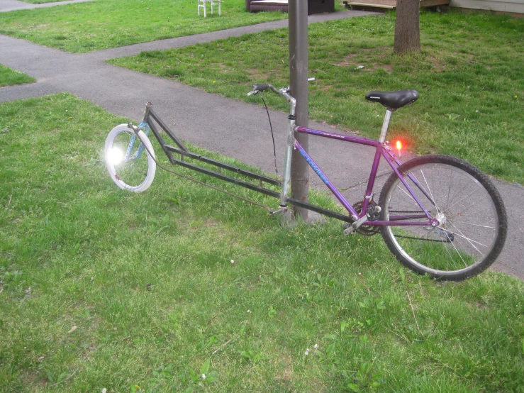 a purple bicycle is on a leash with a light on it