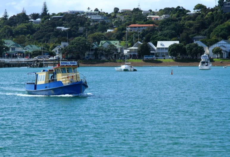 a blue boat with a yellow top sails down the water