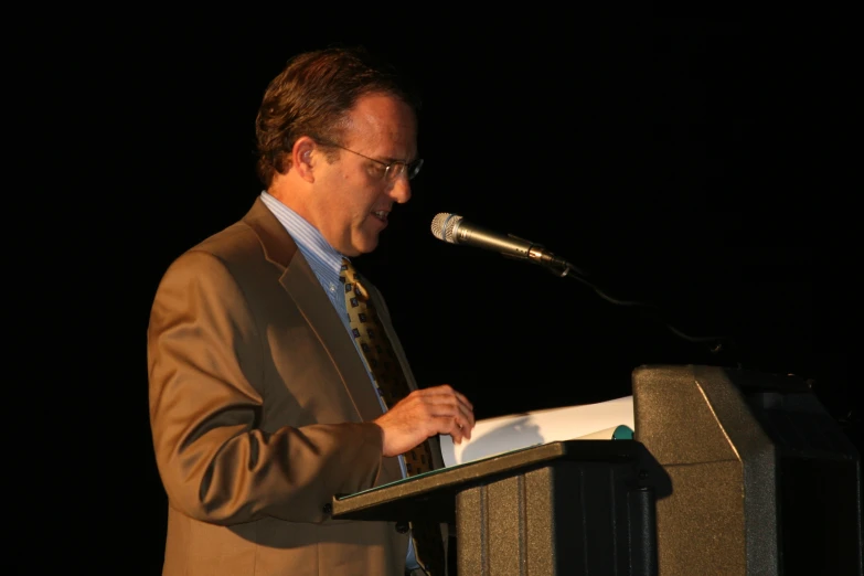 a man standing at a podium talking into a microphone