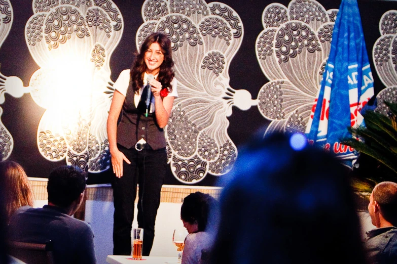 a woman with microphone in front of a crowd