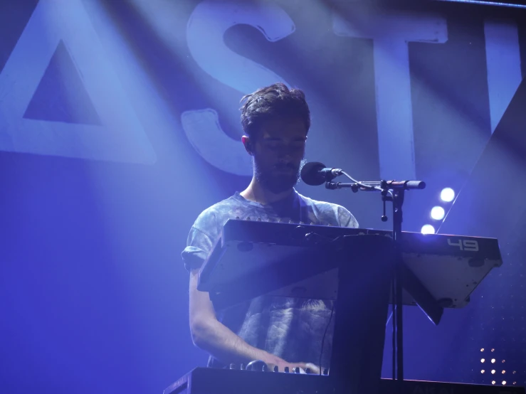 a man with a microphone playing piano on stage