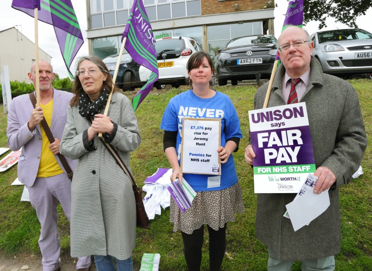 a group of people standing in the grass holding signs