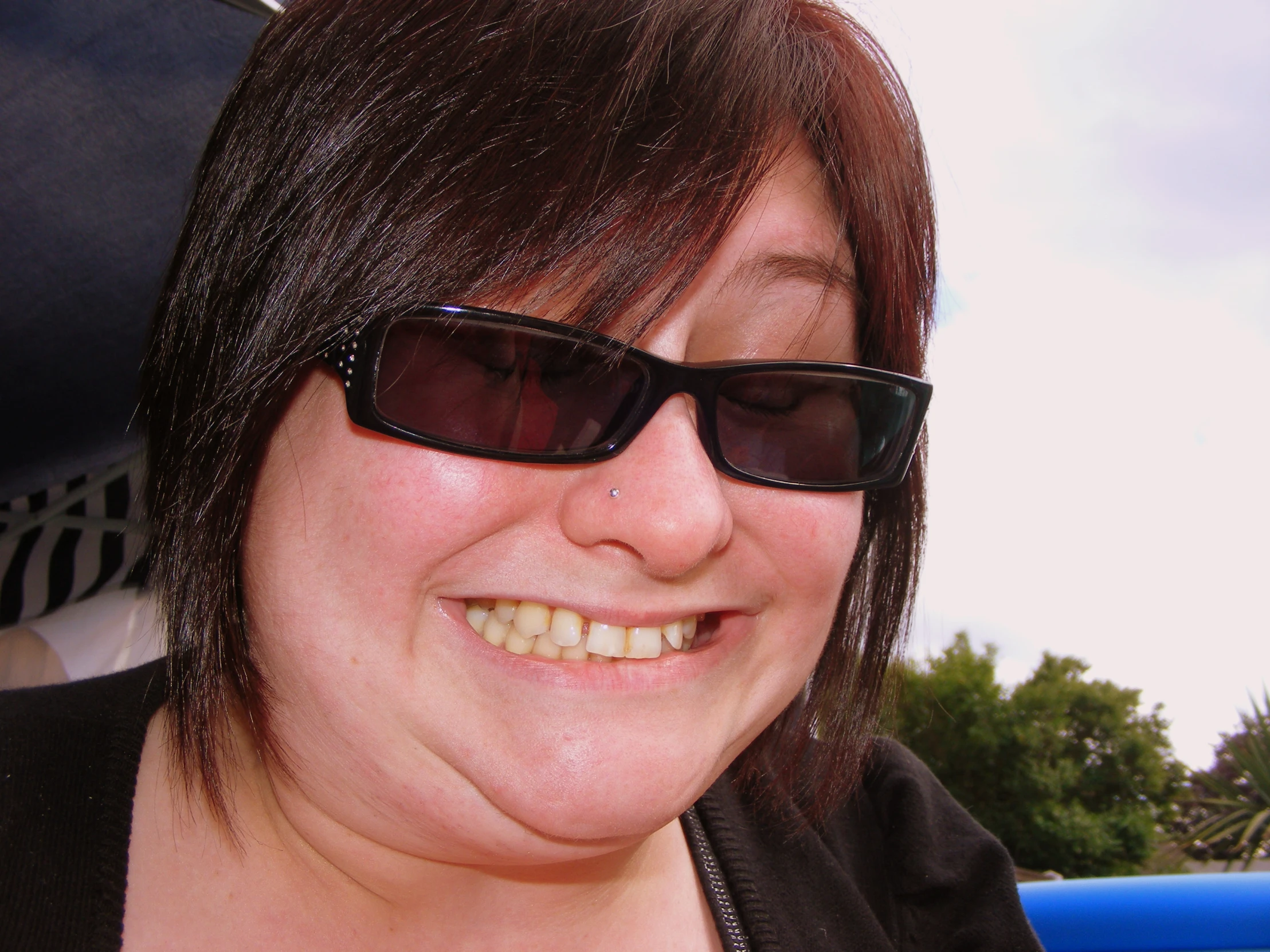 a woman wearing shades on top of a bench