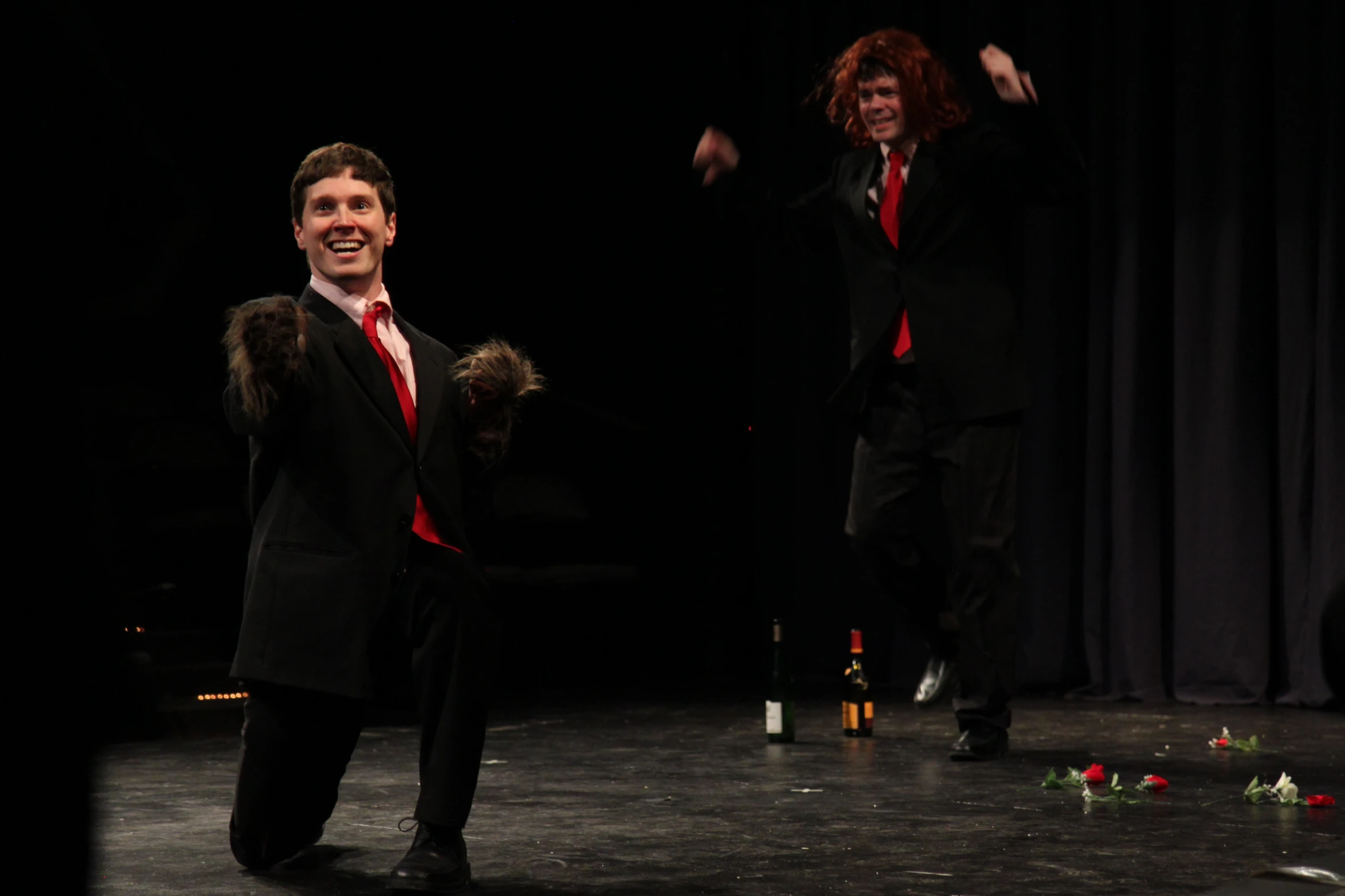 two men in tuxedos perform with wine bottles