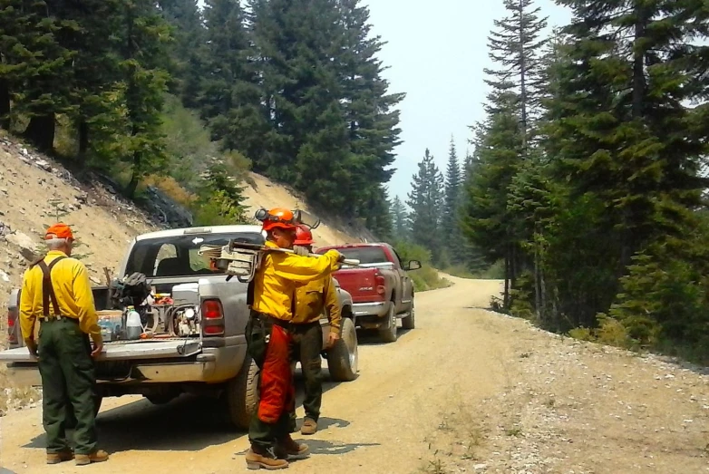 a couple of men standing near a truck on a dirt road