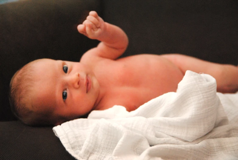 a newborn baby laying on a brown couch