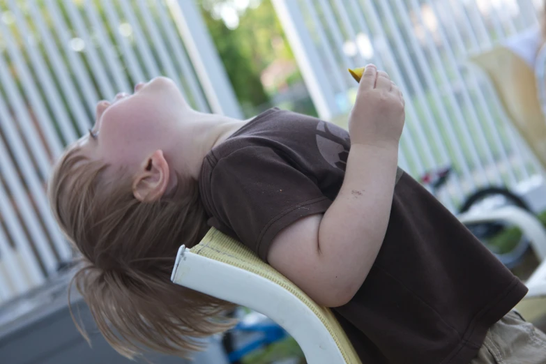 a boy eating a piece of fruit sitting on top of a chair