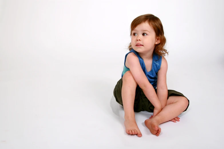 a small girl sitting on the floor in front of a white background