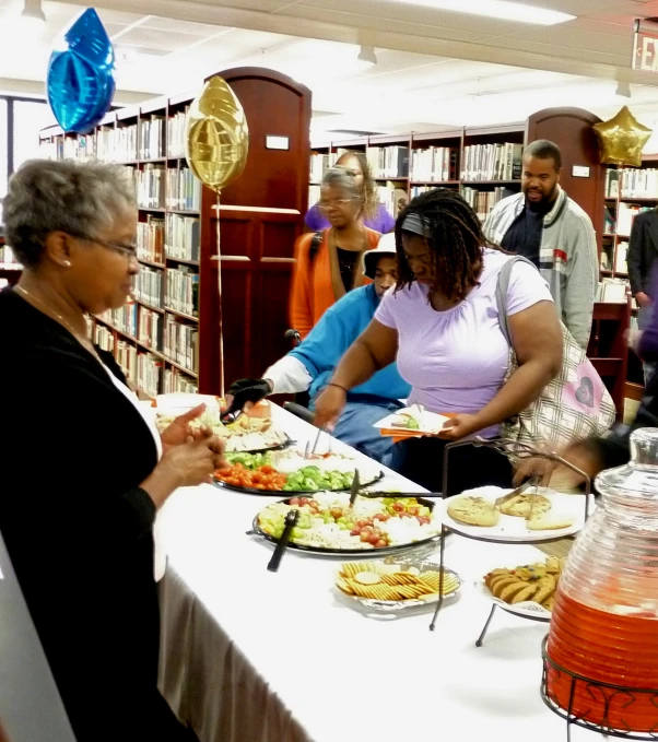 a group of people serving themselves food at a table