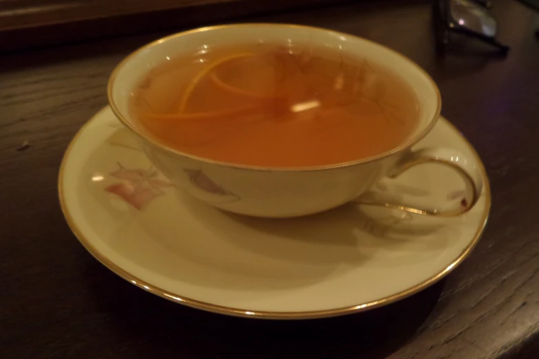 a teacup filled with orange juice on top of a saucer