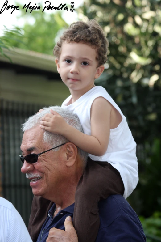 an older man carrying a little boy on his shoulders