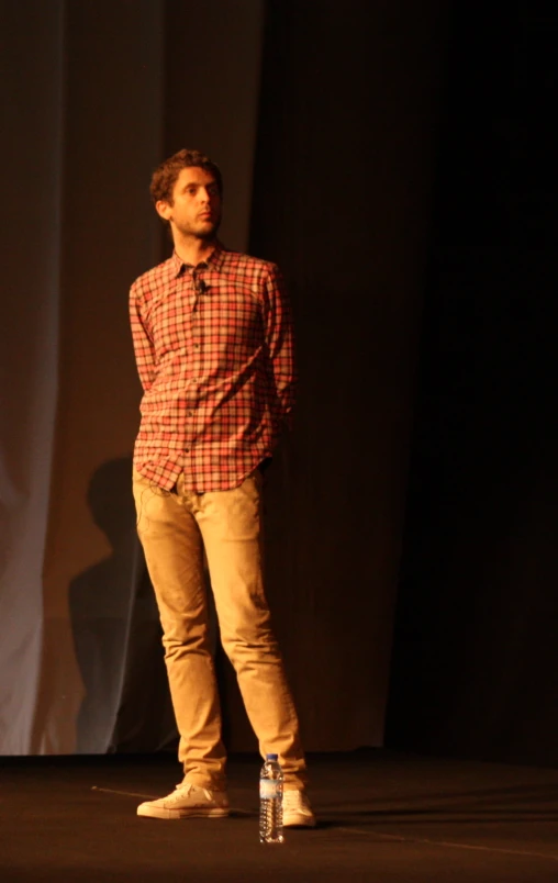 a man stands alone on stage next to water bottle