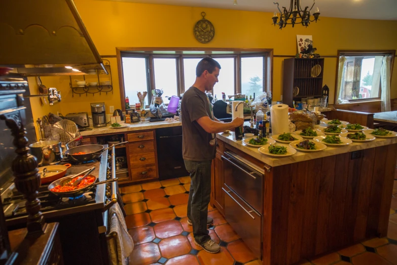 man in kitchen with dishwasher and counter full of dishes