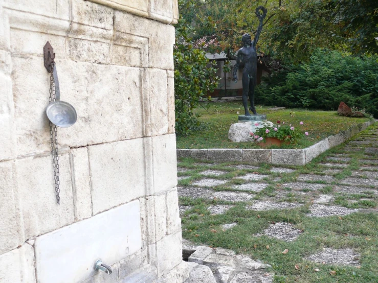 a stone wall and yard with an ornamental statue on it