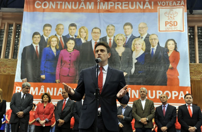 a man in a suit and tie speaks into the microphone