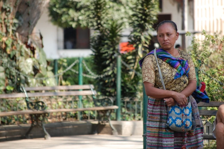 a woman sitting on a bench holding a small purse