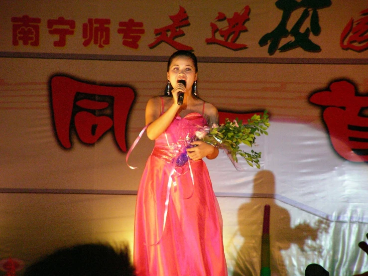 a woman holding flowers standing on stage next to an audience