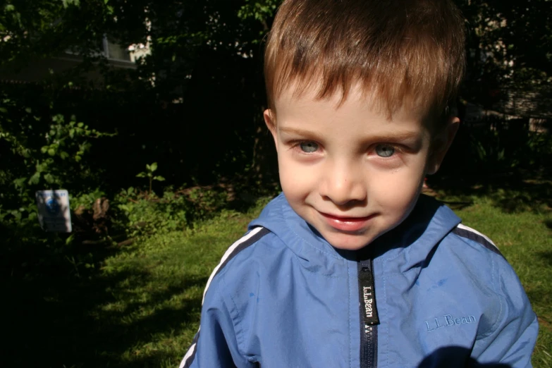 a child smiles as he stands in the sun