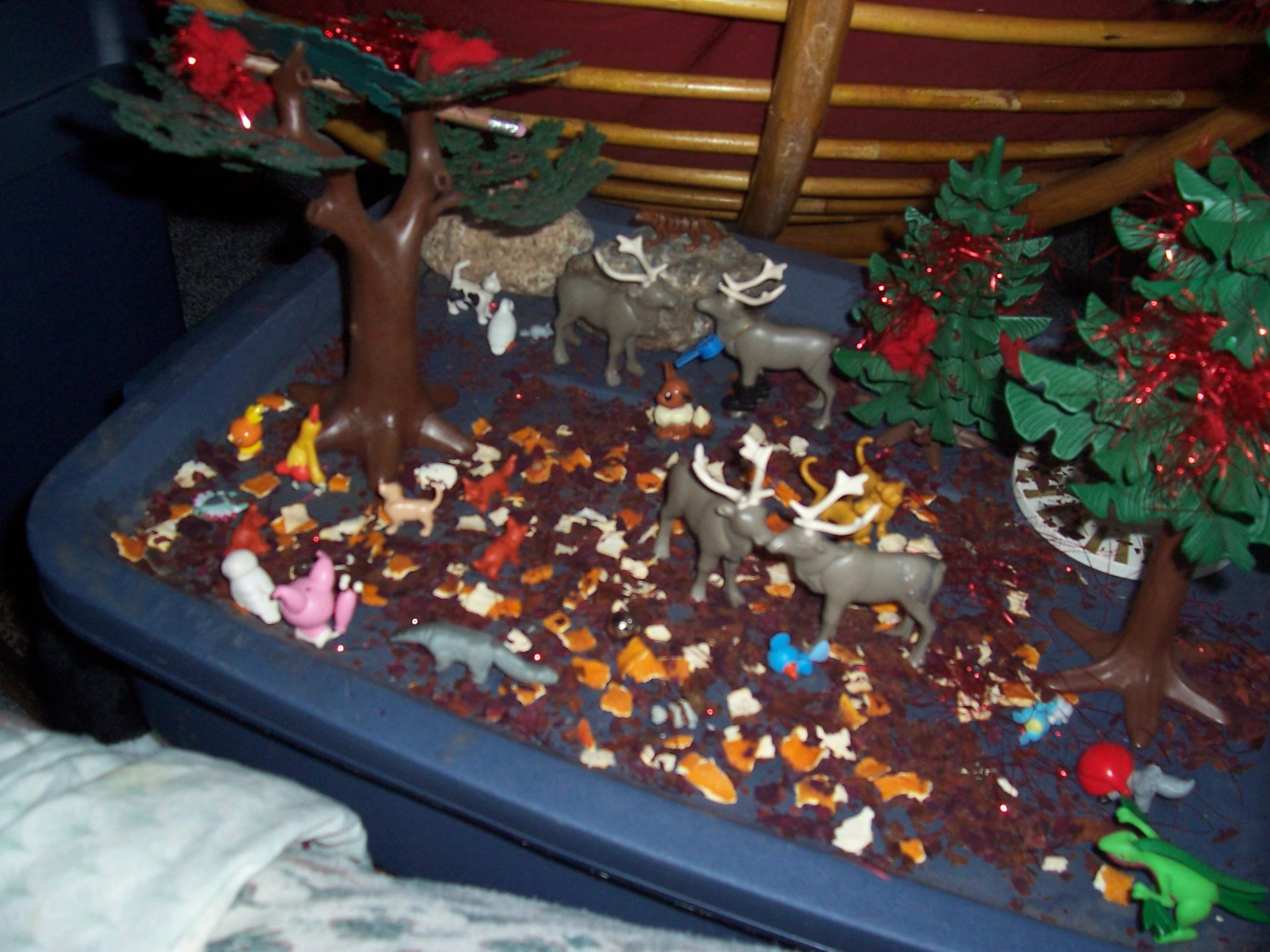 a play table with plastic figurines including animals and trees