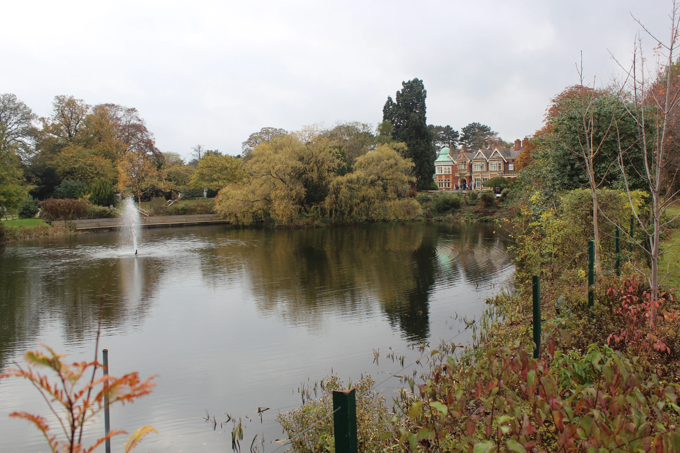 a pond with a large fountain in it surrounded by trees