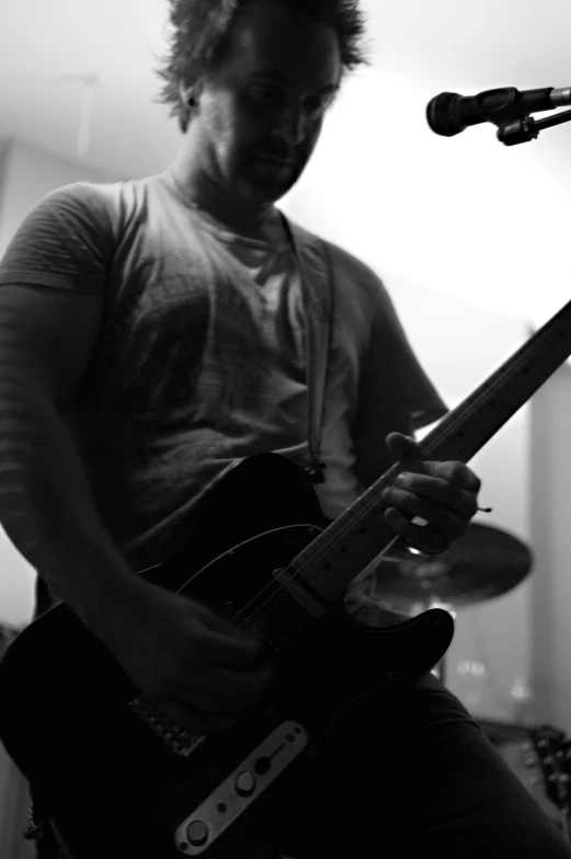 man playing a guitar while singing into a microphone