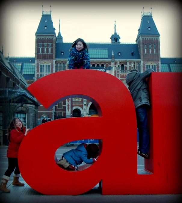 two children standing on the big red letters of a building