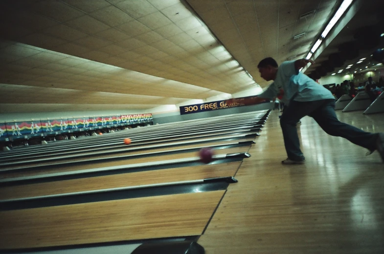 man standing in a bowling alley waiting for a ball