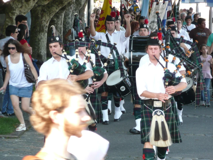 a man in white shirt and kilt walking with other men