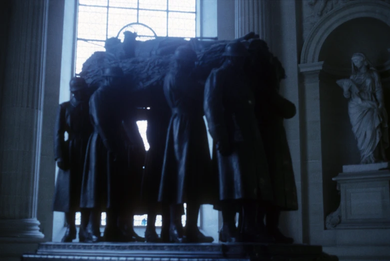 three statues standing in front of a large window