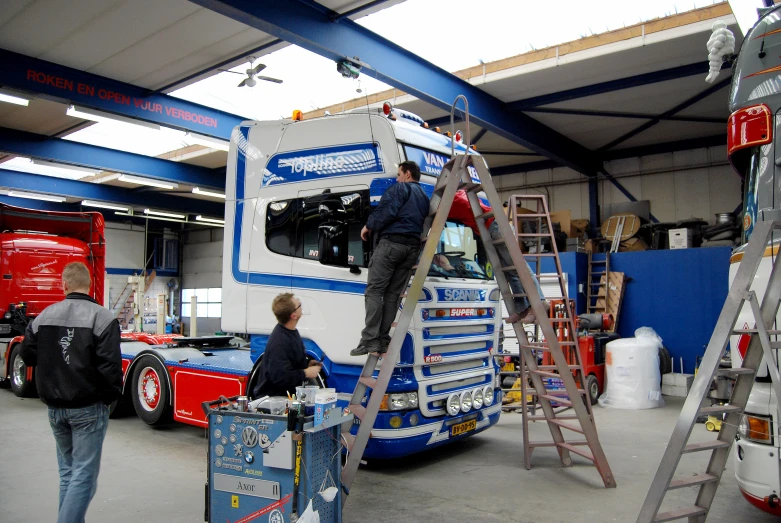 the two men are painting the side of a large bus