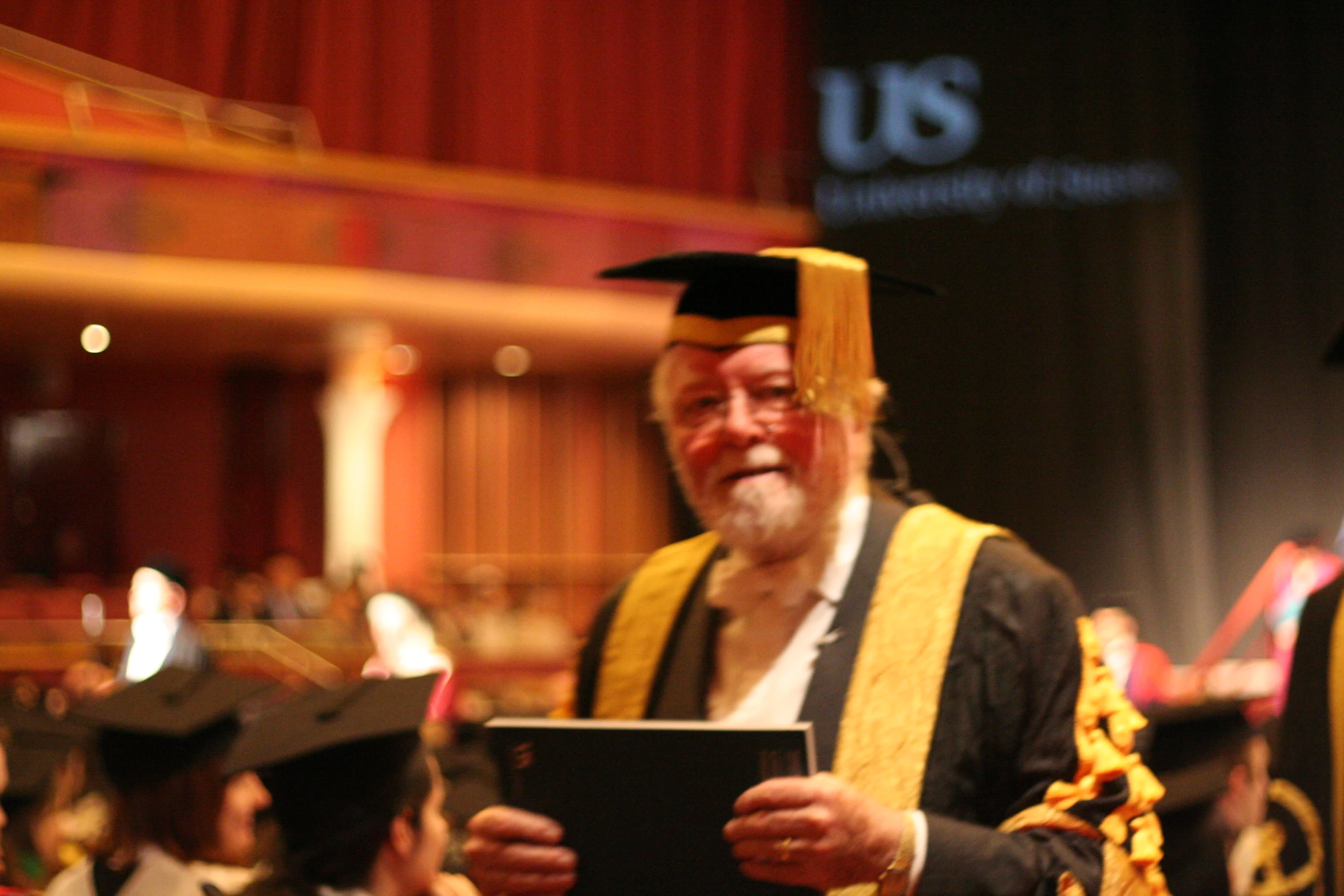 a man in graduation gown reading his book