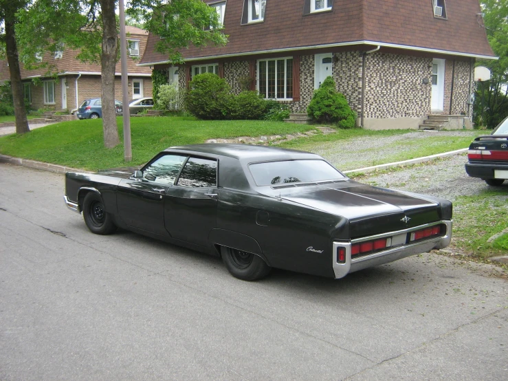 an older, black car parked on the side of a street