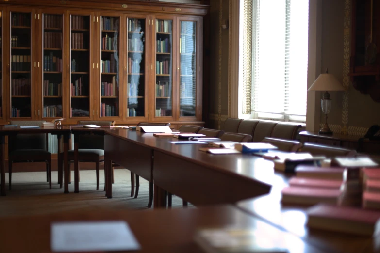 the table has several books on it and in front of the bookshelf