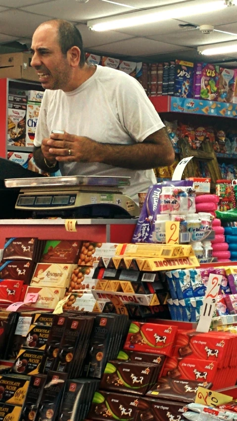 two men stand at a grocery store with some chocolates in front