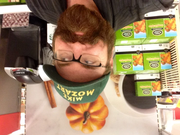 a bearded man with glasses and a green hat is posing in front of a display of pumpkins