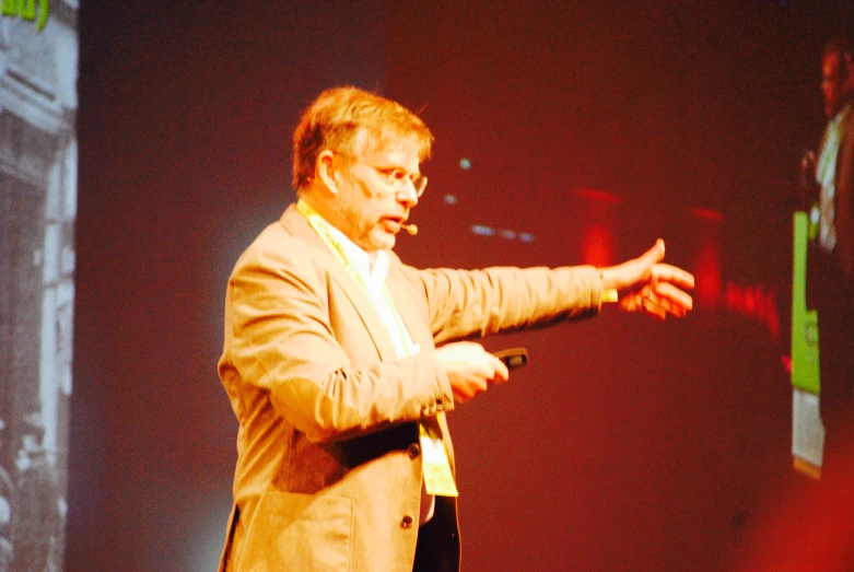 a man stands on stage with his hands out and gestures