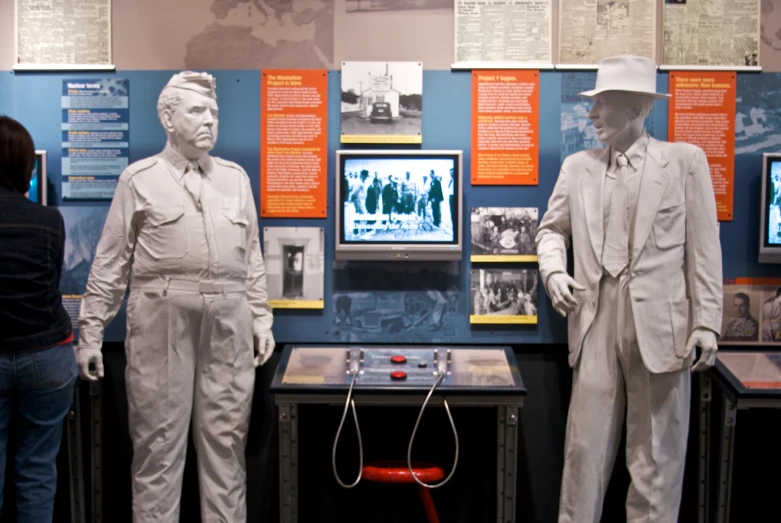 three statues of people standing in front of tv