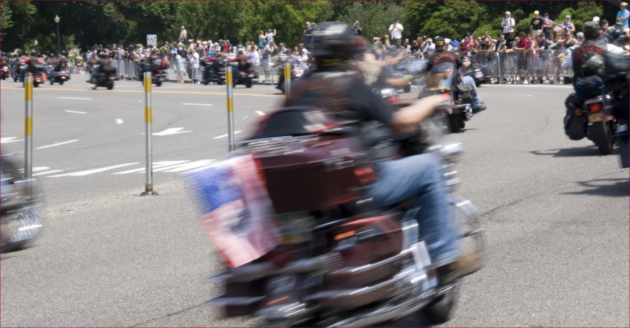 people are riding motorcycles down the road and there is a lot of spectators